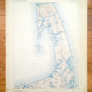 Può includere: Una mappa vintage di Cape Cod, Massachusetts, con toni blu e beige. La mappa mostra la costa, le città e le strade. Il titolo "Massachusetts" è visibile in alto. Proviene dal Dipartimento degli Interni.