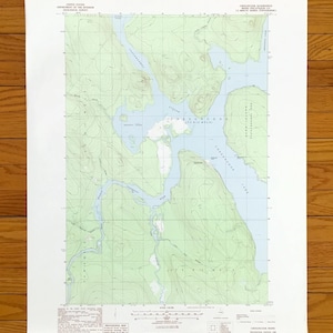 Könnte beinhalten: Eine topografische Karte der Gegend um Checuncook, Maine. Die Karte zeigt den Checuncook-See und die Umgebung, einschließlich der Städte Chesuncook und Moosehorn. Die Karte ist auf weißem Hintergrund mit grünen Linien und Text gedruckt.