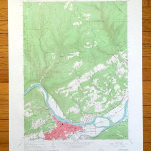 Puede incluir: Un mapa topográfico vintage de Lock Haven, Pensilvania, que muestra el área circundante con líneas verdes y marrones que indican la elevación y los ríos. El mapa está titulado "Lock Haven, PA" e incluye el texto "Geography Department Map Library, U.S. Geological Survey, 7.5 Minute Series".