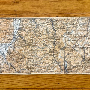 以下が含まれることがあります： ドイツの黒い森地域のヴィンテージマップで、地理的特徴と町が示されています。地図はクリーム色の紙に白黒で印刷されています。地図のタイトルは「シュバルツヴァルト」で、「Anknüpfung der weiteren Topographischen Karten」と「1:125.000」のテキストが含まれています。