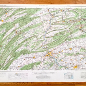 Puede incluir: Un mapa vintage de Harrisburg, Pensilvania, que muestra carreteras, ríos y características del terreno. El mapa está impreso en papel blanco con detalles en verde, rojo y amarillo. El mapa está titulado "HARRISBURG" en la parte superior central.