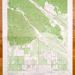 May include: A vintage topographic map of the Devore, California area. The map shows the San Bernardino Mountains, the Mojave River, and the town of Devore. The map is printed in green and brown on a white background.