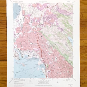 May include: A detailed topographic map of Richmond, California, featuring a blend of pink, green, and blue hues. The map shows roads, buildings, and natural features, with the city name prominently displayed. The map is printed on white paper.