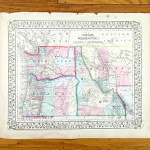Könnte beinhalten: Antike Karte von Oregon, Washington, Idaho und Montana mit dekorativem Rahmen. Die Karte zeigt Bundesstaaten in verschiedenen Farben, darunter Rosa, Blau und Grün, mit dem Text "BRITISH AMERICA" oben.