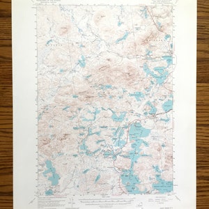 May include: A vintage topographic map of the Saint Regis Quadrangle, New York, featuring a detailed depiction of the area's terrain, including lakes, rivers, and elevation contours. The map is printed on white paper with blue and brown lines.