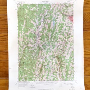 Puede incluir: Un mapa topográfico de una zona de Vermont, con curvas de nivel, áreas verdes que representan bosques y azules que indican cuerpos de agua. El mapa está impreso en papel blanco y muestra la elevación del terreno.