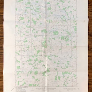 Puede incluir: Un mapa topográfico vintage de la zona de Ramsey, Minnesota. El mapa está impreso en papel blanco y muestra el terreno con líneas verdes y líneas de contorno marrones. El mapa se titula "Ramsey Quadrangle" e incluye el texto "UNITED STATES DEPARTMENT OF THE INTERIOR GEOLOGICAL SURVEY" y "STATE OF MINNESOTA DEPARTMENT OF ADMINISTRATION".