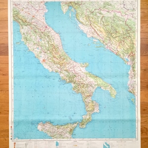 May include: A vintage map of Italy, printed on paper with a blue background and green and brown lines representing land features. The map shows the Italian peninsula, Sicily, and Sardinia. The map is titled "PRIM" and has a date of "14-00-59" in the top right corner.
