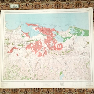May include: A vintage map of San Juan, Puerto Rico, showing the city's layout and surrounding areas. The map is printed on paper and features a light blue background with red and green markings.