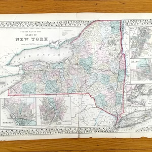 May include: Antique map of New York State, featuring detailed county outlines and city insets. The map is printed on aged paper with a decorative border and the title "County Map of the State of New York". The map is displayed on a wooden surface.