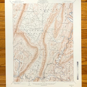 May include: A vintage topographic map of the Everett, Pennsylvania area. The map shows the location of roads, rivers, and other geographical features. The map is printed in black and white on a cream-colored paper.