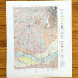 May include: Areal geology map with a detailed, colorful depiction of the landscape. The map features various colors and patterns, including shades of green, pink, and brown, with text labels and a legend. The map is on a white paper.