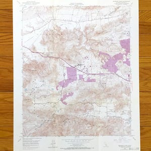 Può includere: Una carta topografica dello United States Geological Survey del quadrante di Newbury Park, in California. La mappa presenta curve di livello dettagliate, ombreggiature del terreno marroni e aree viola urbanizzate.