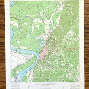 以下が含まれることがあります： ミシシッピ州ビックスバーグのヴィンテージ地形図。地図は、緑と茶色の色で土地の特徴を表し、ミシシッピ川が街を蛇行して流れている様子を示しています。地図のタイトルは「ビックスバーグ、ミシシッピ」で、縮尺と凡例が含まれています。