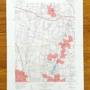 Può includere: Una mappa topografica vintage dettagliata con linee, strade e aree ombreggiate. La mappa presenta evidenziatori rossi e blu, con testo che indica caratteristiche geografiche e nomi di luoghi. La mappa è su carta bianca.