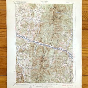 May include: A vintage topographic map of a mountainous region, featuring contour lines, rivers, and place names such as Richmond and Stowe. The map is printed on aged paper with a faded color palette, showing signs of wear.