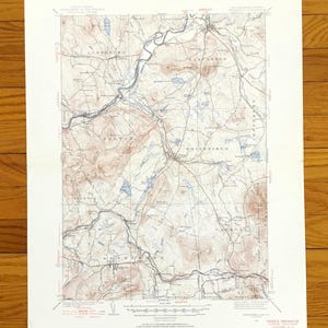 Puede incluir: Un mapa topográfico antiguo con líneas de contorno detalladas, ríos y nombres de lugares. El mapa presenta una paleta de colores marrón, azul y blanco, con texto que indica las características geográficas. El mapa está impreso en papel envejecido.