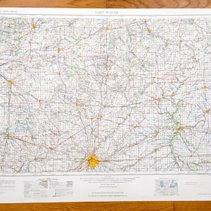 May include: A vintage map of Fort Wayne, Indiana, with a grid pattern and roads marked in red and yellow. The map is printed on white paper and has a title at the top that reads "FORT WAYNE".
