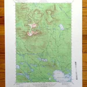 May include: A vintage topographic map of the Millinocket Lake area in Maine, USA. The map shows the location of Mount Katahdin, Baxter State Park, and the surrounding area. The map is printed in green, brown, and blue.
