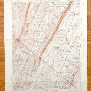 May include: A vintage topographic map of West Virginia, featuring detailed contour lines and geographical features. The map is printed in shades of brown and tan, with red lines indicating roads and boundaries. The map includes text at the top and bottom.