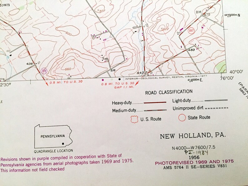 Op de afbeelding: Een zwart-witte kaart van New Holland, Pennsylvania, met een paarse omtrek van de staat. De kaart toont wegen, hoogte en andere geografische kenmerken. De kaart is getiteld "New Holland, PA." en bevat de datum "PI-1984 1956".