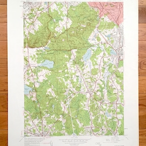 May include: A vintage topographic map of the Blue Hills, Massachusetts, showing the area around the towns of Canton, Milton, and Randolph. The map is printed in green, brown, and red, and includes details such as roads, rivers, and elevation.