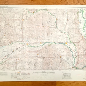 Peut inclure: Une carte ancienne de Fremont, avec le titre bien en évidence. La carte présente des informations topographiques détaillées, notamment les rivières, les routes et les courbes de niveau. La palette de couleurs est discrète, avec des nuances de beige, de brun et de vert. La carte est imprimée sur du papier vieilli.
