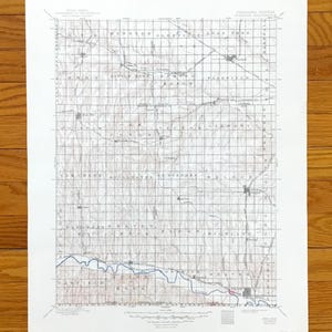Pode incluir: Um mapa topográfico vintage de Nebraska, Kansas, com um padrão de grade e detalhes da paisagem. O mapa inclui nomes de lugares e curvas de nível, impresso em papel envelhecido. O mapa é exibido em uma superfície de madeira.