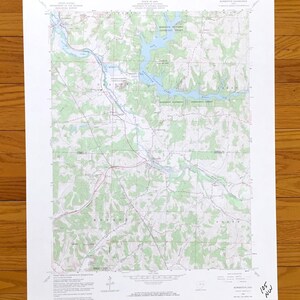 May include: A detailed topographic map with contour lines, water features, and green shaded areas representing vegetation. The map shows a river, lakes, and the surrounding terrain. The map is printed on white paper and is labeled with place names and grid lines.