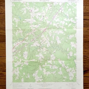 Può includere: Una mappa topografica vintage degli Stati Uniti, che mostra l'area intorno alla città di "Louisa" in Virginia. La mappa è stampata su uno sfondo verde chiaro con linee marroni che indicano strade e fiumi. La mappa è intitolata "Louisa, Virginia" e include il testo "United States Department of the Interior Geological Survey" e "Commonwealth of Virginia, Division of Mineral Resources."