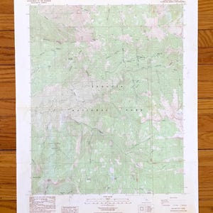 May include: A vintage topographic map of Sequoia National Park, featuring contour lines, elevations, and geographical details. The map includes the text "Sequoia National Park" and is printed on aged paper. The map is on a wooden surface.