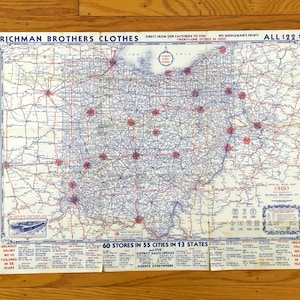 May include: A vintage Richman Brothers Clothes road map of Ohio featuring a blue and white grid of highways, red star markers for store locations, and text listing 60 stores in 55 cities across 13 states, all priced at $22.50.