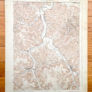 Pode incluir: Mapa topográfico vintage com linhas de contorno castanhas, rios e estradas. O mapa, impresso em papel envelhecido, mostra uma paisagem detalhada com texto indicando características geográficas e nomes de lugares. O mapa é do Departamento do Interior.