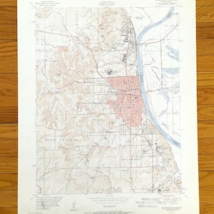 May include: A vintage topographic map showing a city, with detailed contour lines, roads, and a river. The map is printed on aged paper, with a red-shaded area indicating the city centre. The map includes the text "United States Department of the Interior".