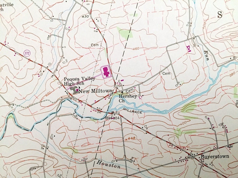 Op de afbeelding: Een vintage kaart van een landelijk gebied met een rivier, wegen en gebouwen. De kaart toont de locatie van Pequea Valley High Sch, New Milltown, Hershey Ch en Buyerstown. De kaart bevat ook een schaal en een legenda.