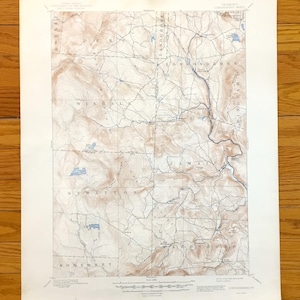 Könnte beinhalten: Eine Vintage-Topografische Karte eines ländlichen Gebiets mit Höhenlinien, Ortsnamen und Gewässern. Die Karte ist in Braun- und Blautönen auf gealtertem Papier gedruckt, mit Ortsnamen wie Londonderry und Stratton. Die Karte liegt auf einer Holzoberfläche.