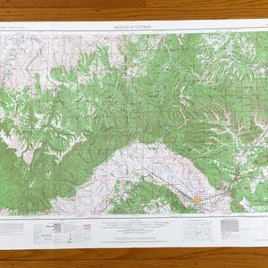 May include: A detailed topographic map of Grand Junction, featuring green shaded areas representing forests and mountainous terrain. The map includes grid lines, roads, and text, with the title "GRAND JUNCTION" at the top.