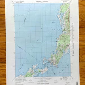 Può includere: Una mappa vintage di Woods Hole, Massachusetts, che mostra la costa e le isole circostanti. La mappa è stampata su carta blu con linee e testo marroni. La mappa è intitolata "Woods Hole Quadrangle" e include il testo "Commonwealth of Massachusetts" e "United States Department of the Interior Geological Survey".