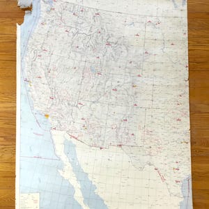 以下が含まれることがあります： アメリカ西部のヴィンテージVFRプランニングチャート。州、都市、地理的特徴が表示されています。地図は、青と白の配色で、古くなった紙に印刷されています。「VFR Planning Chart」というタイトルが上部に表示されています。