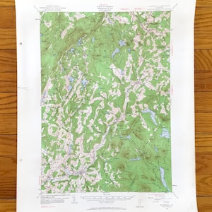 以下が含まれることがあります： 緑と白の地形、等高線、湖、地名が特徴のヴィンテージ地形図。 地図は、上部と下部にテキストが印刷された、古くなった紙に印刷されています。タイトルには「Plainfield Quadrangle, Vermont」が含まれています。