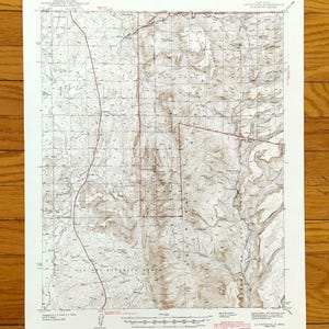 May include: A vintage topographic map with detailed contour lines and grid patterns. The map features shades of brown and tan, with text indicating the map's title and scale. The paper has a slightly aged appearance.