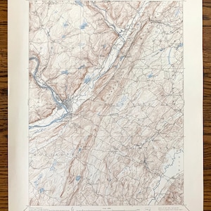 Puede incluir: Un mapa topográfico antiguo de la zona de Nueva York-Nueva Jersey-Pensilvania, con líneas de contorno detalladas, ríos y pueblos. El mapa está impreso en tonos marrones y azules, con texto que indica el Departamento del Interior de los Estados Unidos y otra información geográfica.