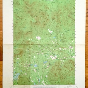 Könnte beinhalten: Eine Vintage-topografische Karte des Gebiets um den Mount Chocorua in New Hampshire. Die Karte zeigt den White Mountain National Forest mit grünen und braunen Höhenlinien, die Höhenunterschiede anzeigen. Die Karte enthält auch Beschriftungen für verschiedene geografische Merkmale wie Flüsse, Seen und Berge.