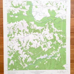 May include: A vintage map of the Woodville, Texas area, printed on a white background with green and blue lines. The map shows roads, rivers, and other geographical features. The map is titled "Geography Department Map Library Woodville, Texas 75979"