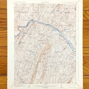 Puede incluir: Un mapa topográfico vintage de la zona de Indian Springs en Virginia Occidental. El mapa muestra el terreno, los ríos y las carreteras de la zona. El mapa está impreso en papel de color crema y tiene una combinación de colores marrón y azul.