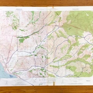 May include: A vintage topographic map showing a mountainous region, with green and tan colours. Blue lines indicate waterways. The map is folded, showing signs of age and wear, and is in centimetres.