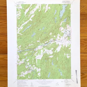 Może przedstawiać: Zabytkowa mapa topograficzna przedstawiająca zielony i biały teren z niebieskimi zbiornikami wodnymi. Mapa jest wydrukowana na postarzanym papierze i zawiera tekst wskazujący, że pochodzi z United States Geological Survey.