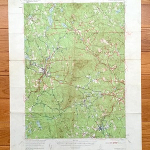 May include: A vintage topographic map of the area around the town of Peterborough, New Hampshire. The map shows roads, rivers, and other geographical features. The map is printed on a white background with green, blue, and red lines.