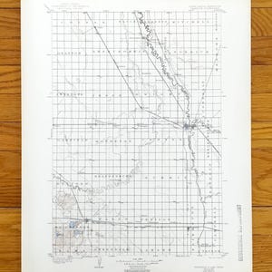 May include: A vintage map with a grid overlay, featuring place names and geographical details. The map is printed on aged paper, with a detailed depiction of the terrain and waterways. The map is from the Geoscience Department.