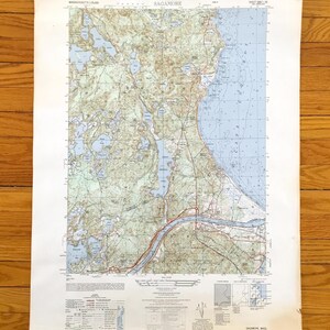 Può includere: Una mappa vintage di Sagamore, Massachusetts, con informazioni topografiche dettagliate. La mappa mostra una regione costiera con acqua blu, terra verde e strade marroni. La mappa è stampata su carta invecchiata e include testo.